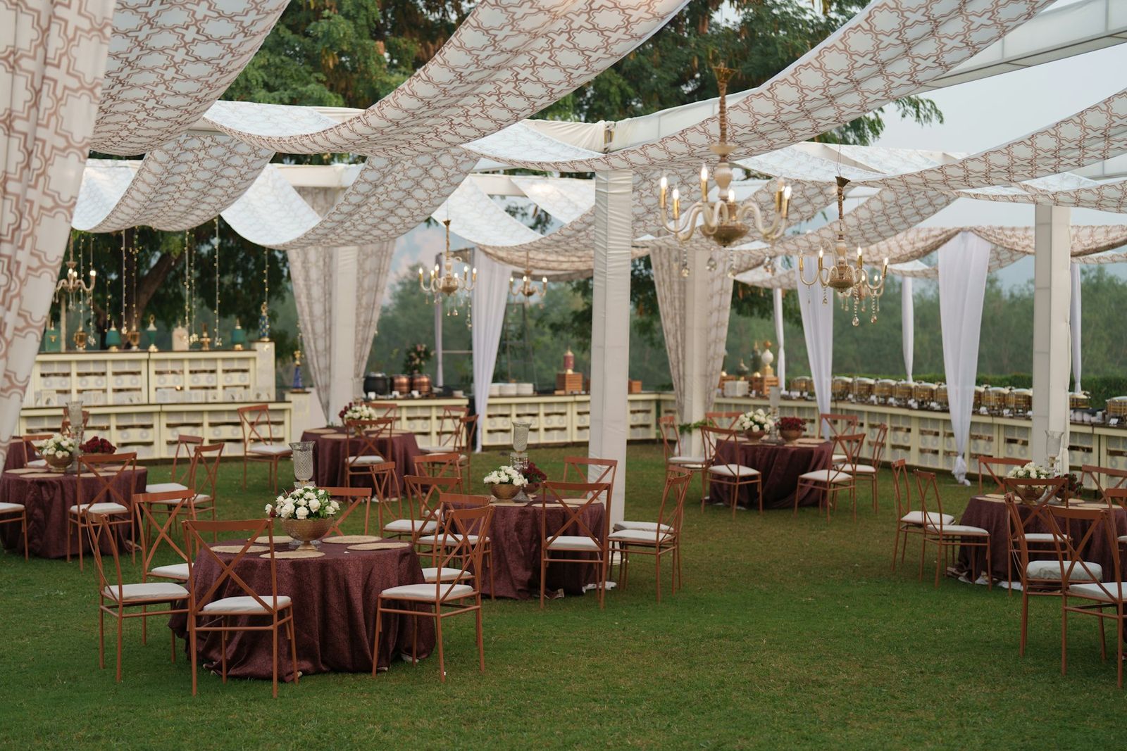 Round tables under a white draped canopy on a lawn