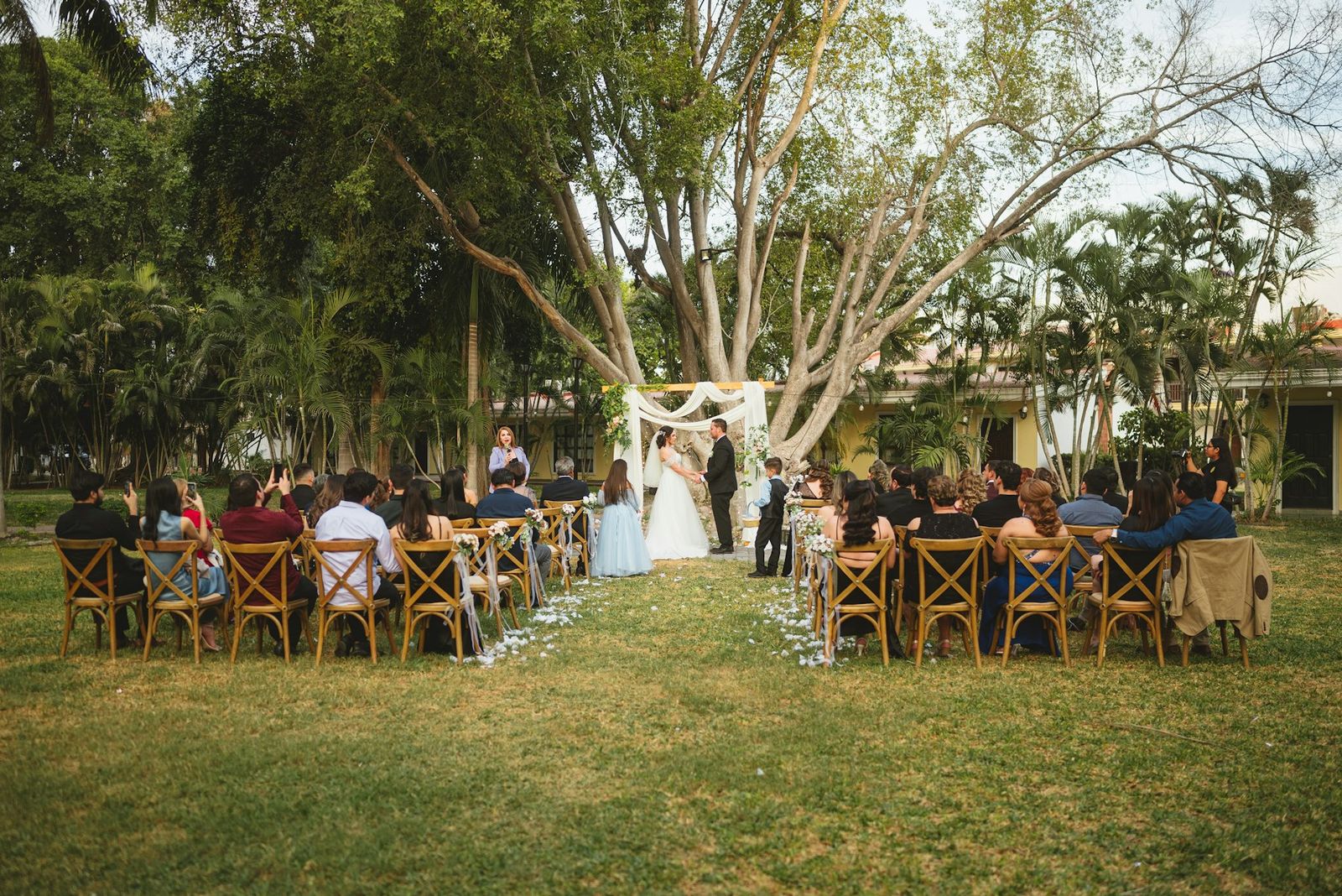 Guests seated on wooden chairs for a ceremony in a garden