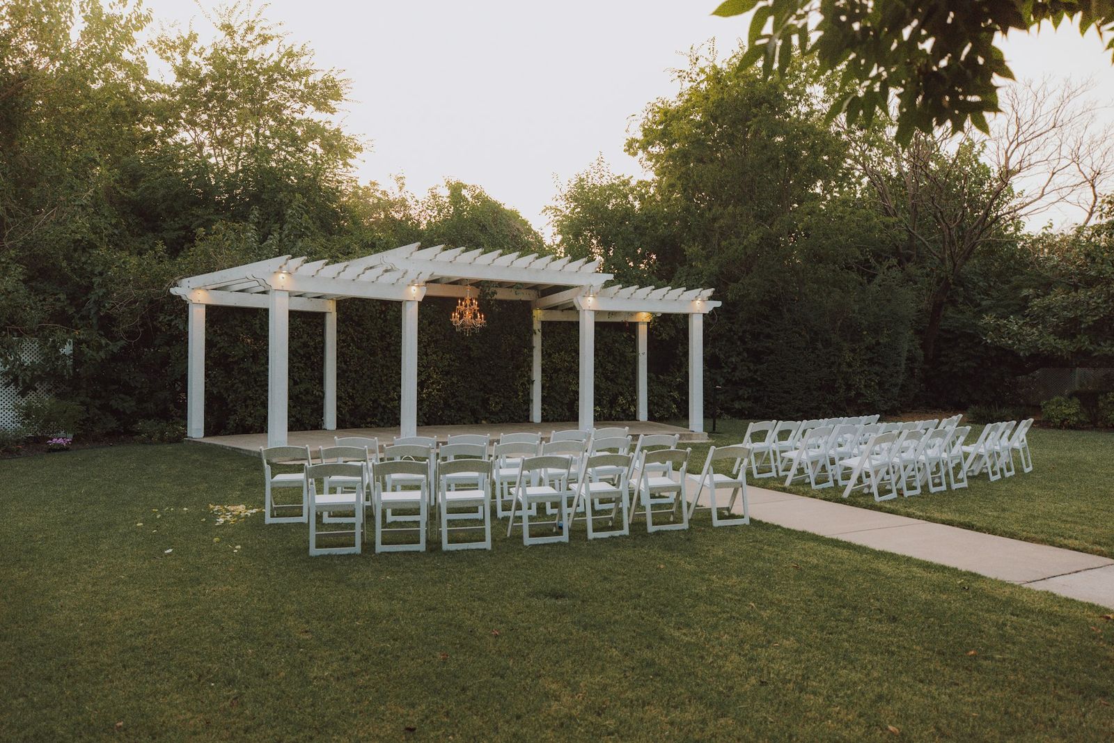 A white gazebo on a garden lawn with chairs