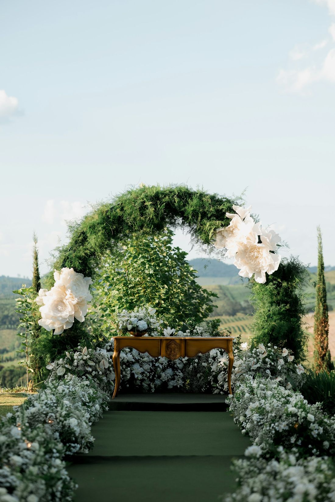 A green and white floral arch with hills behind