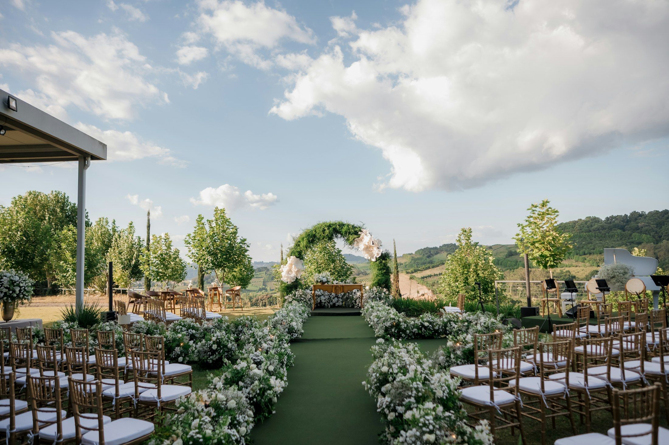 A garden ceremony set up on a green lawn with rolling hills behind